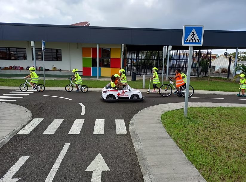 Enfants à vélo, en trottinette et en voiture électrique sur une piste d'éducation routière